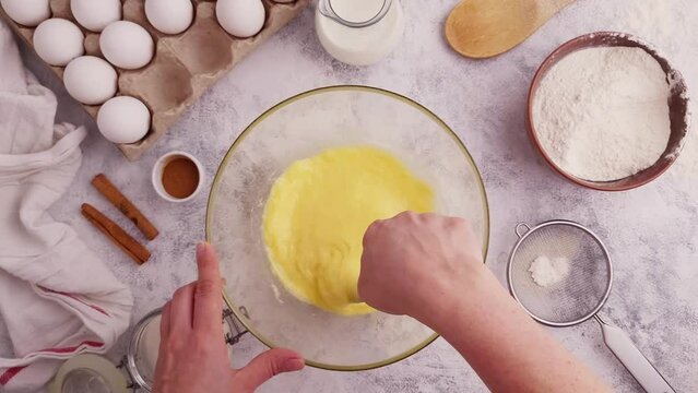 Mixing batter in a glass cup on the table among the ingredients for baking, top view