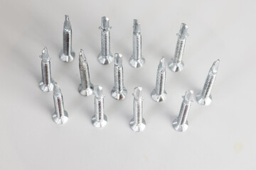 Tapping screws made of steel on gray background, metal screw, iron screw, chrome screw, screws as a background, wood screw, concept industry. copy space for text.