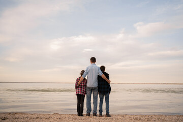 Family, travel, beach, relax, lifestyle, holiday. Family on sunset near ocean, back view. Father...