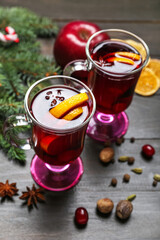 Glasses of aromatic mulled wine on dark wooden table, closeup