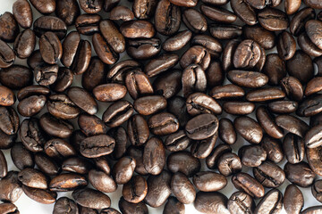 Roasted coffee Beans on white background. Coffee beans close up. Coffee grounds. Freshly roasted coffee beans. Image of a drink made from granules, derived from coffee plant. Copy space for text.