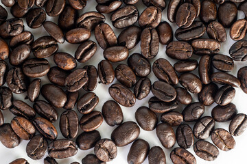 Roasted coffee Beans on white background. Coffee beans close up. Coffee grounds. Freshly roasted coffee beans. Image of a drink made from granules, derived from coffee plant. Copy space for text.