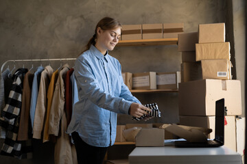 start up small business owner packing clothes in the box at home office. freelance woman seller...
