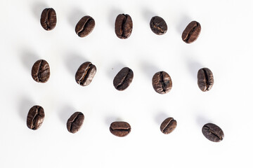 Roasted coffee Beans on white background. Coffee beans close up. Coffee grounds. Freshly roasted coffee beans. Image of a drink made from granules, derived from coffee plant. Copy space for text.