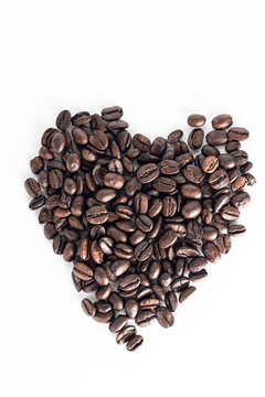 Roasted coffee Beans on white background. Coffee beans close up. Coffee grounds. Freshly roasted coffee beans. Image of a drink made from granules, derived from coffee plant. Copy space for text.