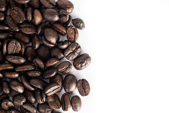 Roasted coffee Beans on white background. Coffee beans close up. Coffee grounds. Freshly roasted coffee beans. Image of a drink made from granules, derived from coffee plant. Copy space for text.