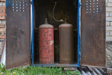 Old gas bottles. Rusty, cobwebbed, and dusty gas storage tanks sit in a metal storage box. There is...