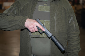 A pistol with a silencer in his hand near the body in the bulletproof vest. 