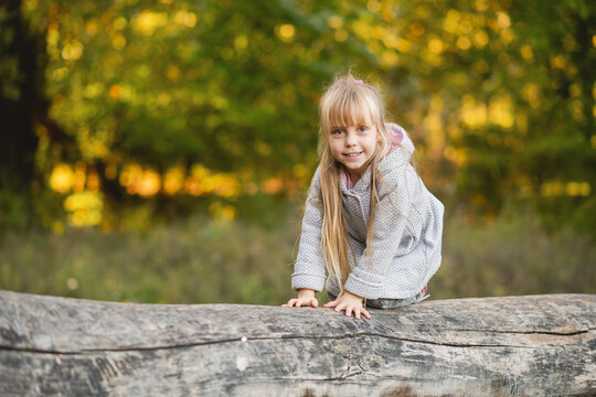 Cute child girl on all fours balances on a fallen log.
