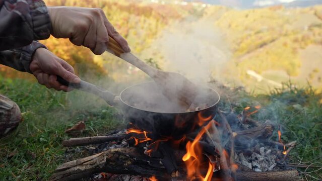 Egg omelet made from freshly picked mushrooms and country ham, 4k video campfire. A man cooks an omelet at the edge of the forest, in a campsite, over a wood fire. Traditional cooking.