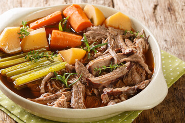 Roast pot of slow cooked beef with vegetables in a spicy sauce close-up in a frying pan on the table. horizontal