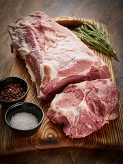 Pork neck meat on a wooden board. Fresh raw pork neck with salt and pepper.