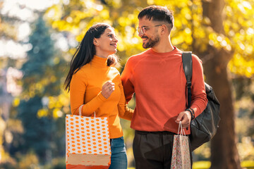 Happy couple with shopping bags in autumn park