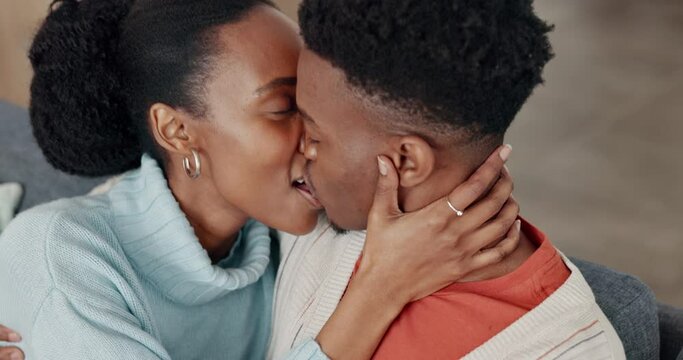 Black couple, laughing and kissing in sofa in house or home living room in love, trust or intimate safety. Smile, happy and talking man and woman bonding in relax communication or sharing comic joke
