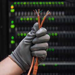Network wires in the hands of a man at the server for data storage, close-up
