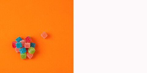 Multicolored variety of sweet jelly candies on orange color background