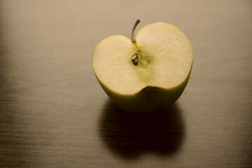 one half of yellow apple.  cut golden apple on wooden table  background.  Sliced apple on the table