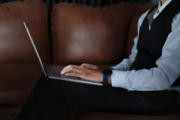 Portrait of a handsome, discreet Asian man sitting on the sofa using a computer