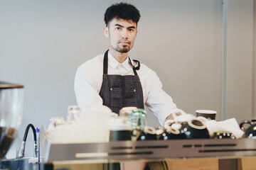 Asian male barista making coffee for customers