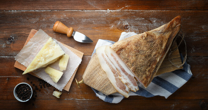 Pecorino cheese, guanciale and pepper on wooden background. Top view, space for text..
