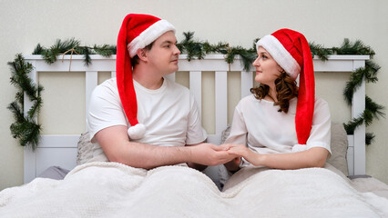 A woman and a man reconcile lying on a bed decorated for Christmas on New Year Eve, family couple...