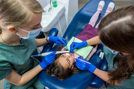 the dentist examine the child's teeth with a camera and display the picture on the screen.