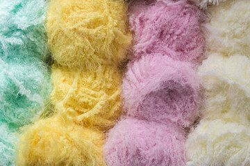 Bright multicolored balls of wool yarn for needlework. The concept of needlework and knitting. Warm cozy background.