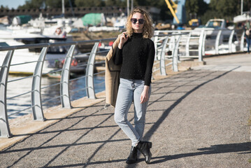 Portrait of a young Caucasian girl in a coat and sunglasses in the city on an autumn day.