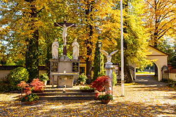 Field shrine aside St. Matthias church, kosciol sw. Macieja, over autumn colors in historic old town quarter of Andrychow in Poland