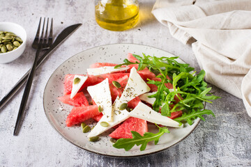 Homemade salad of feta cheese, watermelon and arugula on a plate. Organic diet.