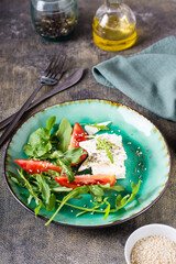 Sliced tomatoes, feta cheese, sesame seeds and arugula leaves on a plate. Organic diet. Vertical