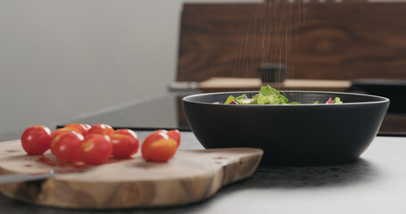 Closeup man making salad with greens , tomatoes and steak in a black bowl
