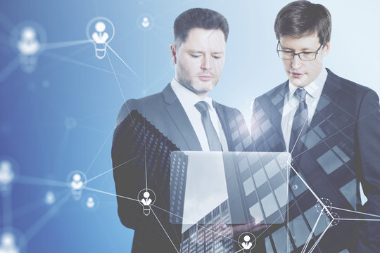 businessmen using laptop computer with abstract glowing people and light bulb network on blurry background. Networking, teamwork, internet communication and social media concept. Double exposure.
