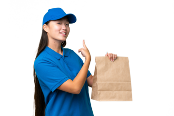 Young Asian woman taking a bag of takeaway food over isolated background pointing back