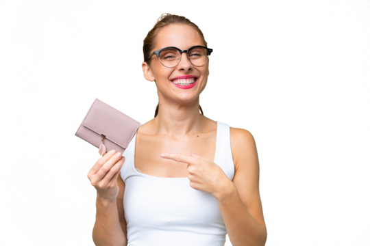 Young caucasian woman holding a wallet over isolated background and pointing it