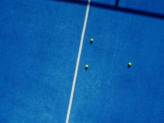 three balls on a blue paddle tennis court, drone aerial view