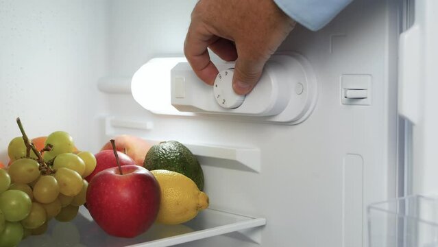 Man Hand Open the Kitchen Fridge Door and Set the Thermostat. Making the Fridge Temperature Control for Optimum Function.
