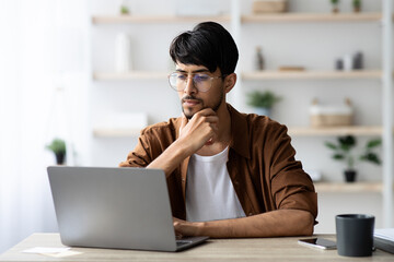 Pensive arabic man employee working on modern notebook