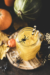 Halloween pumpkin iced cocktails in glass jars on a stone table. Party cocktails. Toned image.