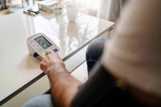 Man Using Blood Pressure Device On Table At Home