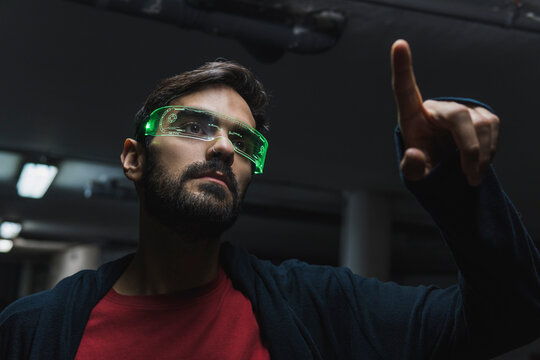 Man wearing futuristic smart glasses touching augmented interface