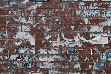 Torn street poster abstract background collage with ripped paper texture on a brick wall