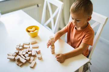 Boy stacking toy blocks on dining table at home