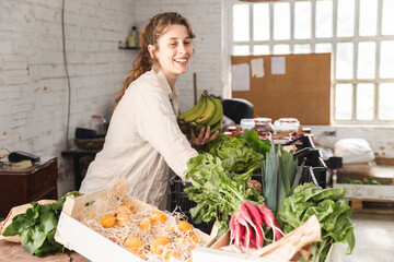 Happy owner picking up vegetables in greengrocer shop