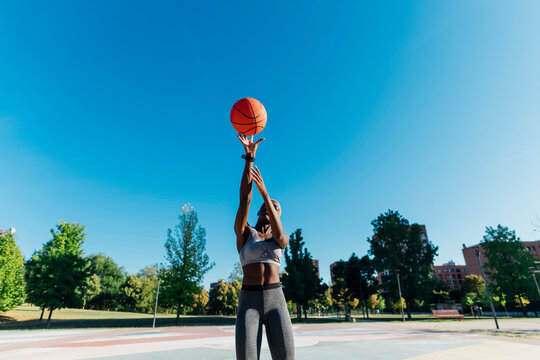 Basketball player throwing ball on sunny day - Powered by Adobe