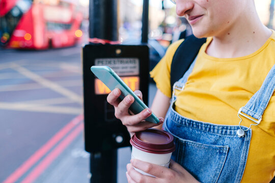 Transgender with disposable coffee cup using mobile phone - Powered by Adobe