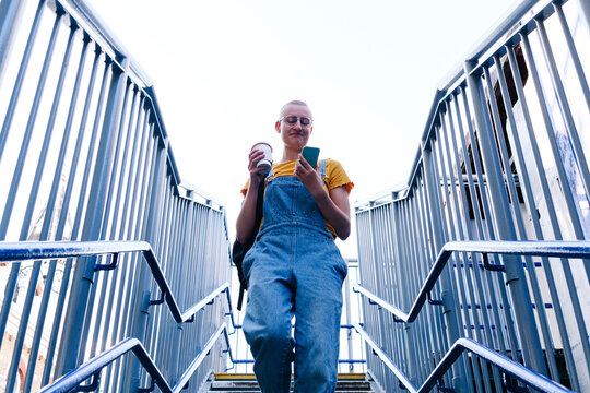 Non-binary person using smart phone on staircase