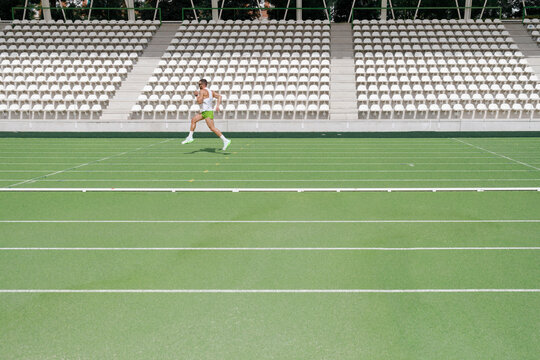 Athlete practicing running on sports track at sunny day