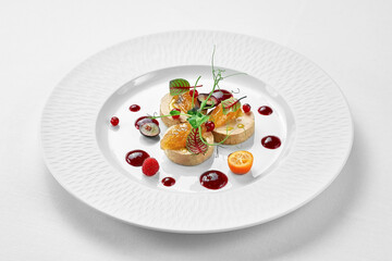 Foie gras with apple confit and berry sauce in a white plate on a white background. Close-up,...