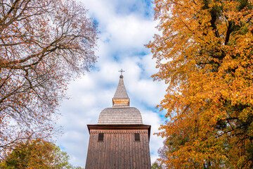 The tower of the historic church made of wood. The church is covered with shingles. Autumn. Polanka Wielka, Poland - obrazy, fototapety, plakaty